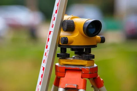 Close-up view of cheap geodesy level device with tower ruler outdoors Stock Photos