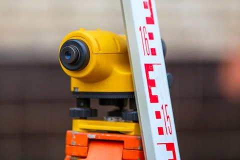 Close-up view of cheap geodesy level device with tower ruler outdoors Stock Photos