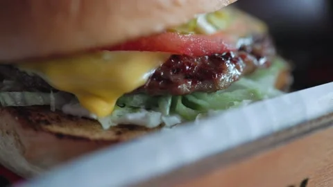 Close up view of cheeseburger with tomato and greens Stock Footage 200478988