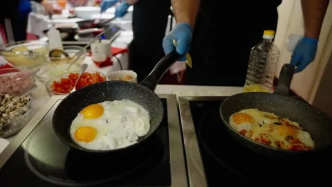Close-up view of a chef preparing sunny side up eggs and a vegetable omelette in Stock Footage 312209636