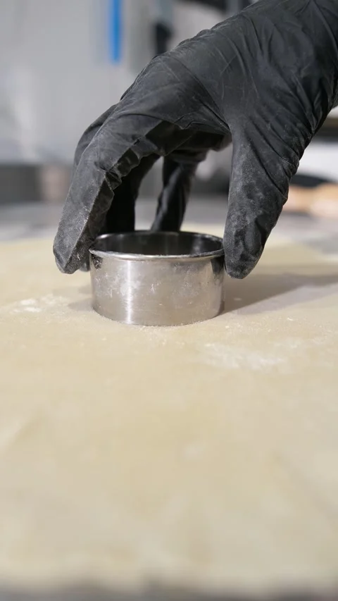 Close up view of a chefs hand in a black glove pressing a metal round cookie Stock Footage 318316667
