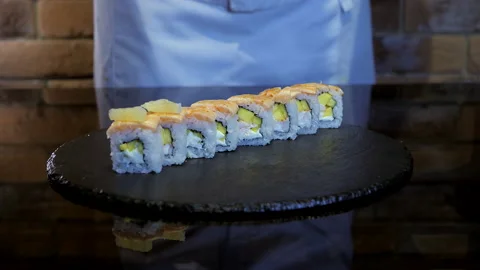Close up view of chef's hand in glove decorates rice rolls with lemon pieces. Stock Footage 133000990