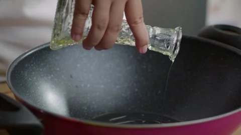 Close-up view of a chef's hand pouring olive oil on a pan. Cooking preparat.. Stock Footage 329703754