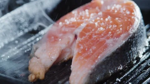 Close up view of A chef's hand squeezes a fresh lemon over a peace of sea fish. Stock-Footage 336588759