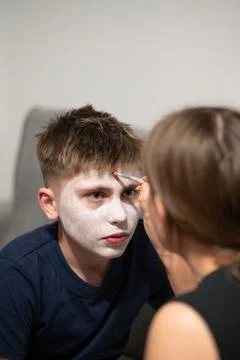 Close-up view of a child getting their face painted white by an adult. The se Stock Photos