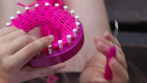 Close-up view of a child knitting on a loom with pink threads Stock Footage 280784040