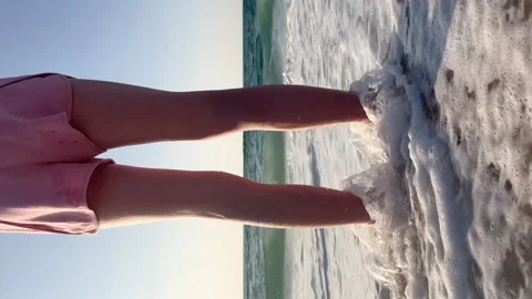 Close up view on child legs standing in the ocean water. Girl standing on the Stock Footage 254629762