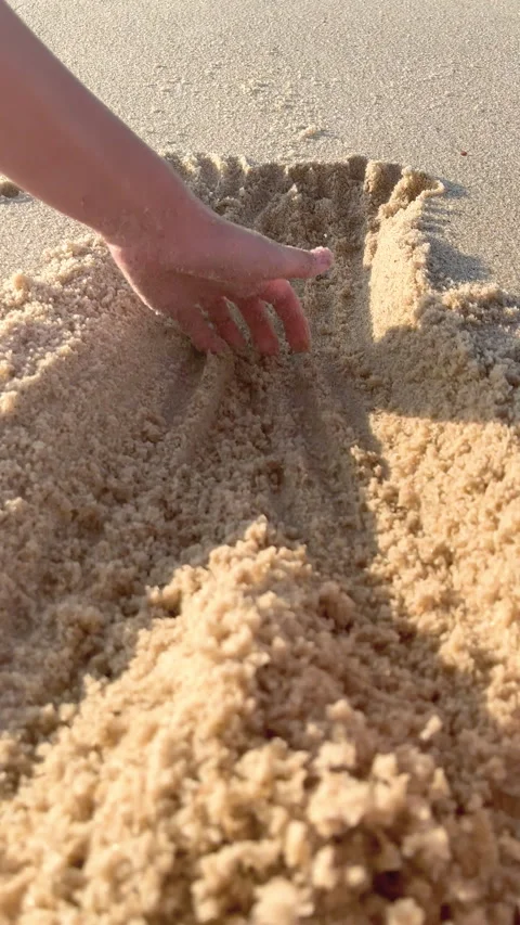 A close up view of a child playing with sand on the beach. Hands knead and sort Video stock 252850672