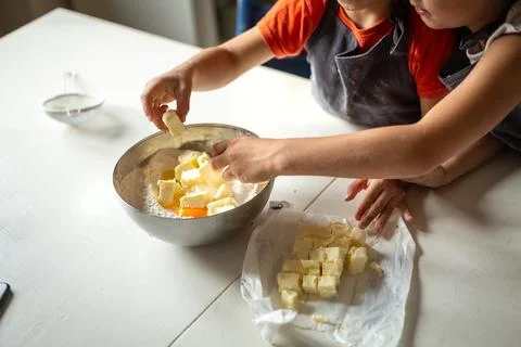 Close view of children hands adding butter to flour Stock Photos