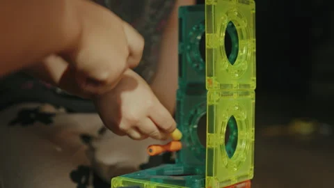 Close-up view of children's hands playing magnetic constructor toy, sitting on Stock Footage 255029008