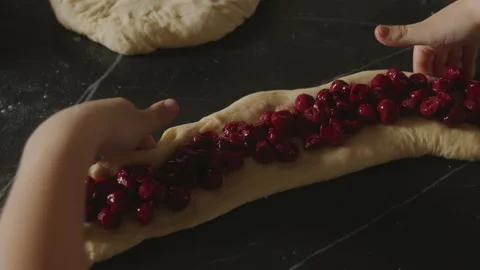 Close-up view of child's hands preparing pie dough, filling it with cherries Stock Footage 238889785