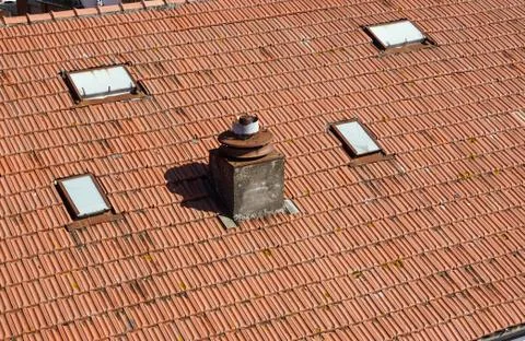 A close up view of a chimney on top of red roof tiles Stock Photos