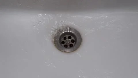 A close-up view of a circular metal drain set into a white sink. 스톡 동영상 325770461