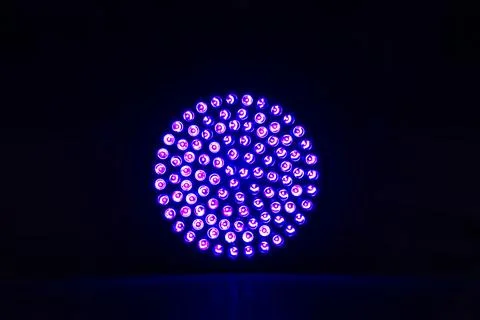 A close-up view of a circular stage light emitting a vibrant purple light. Stock Photos