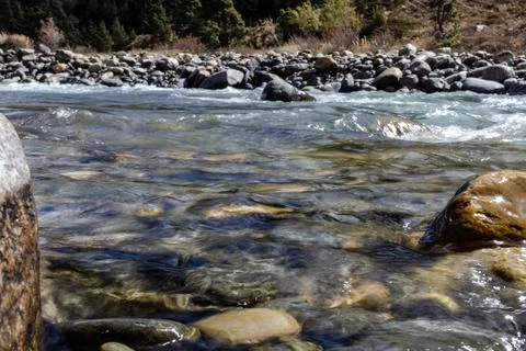 Close up view of clear river with sunlight reflecting on colorful stones an.. 库存照片