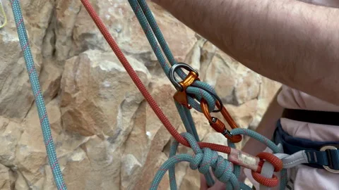 Close up view of climber belaying double ropes on rock face Stock Footage 330590744