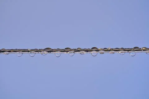 Close up view of clothes line wire with morning rain drops on it. Hard to dry Stock Photos