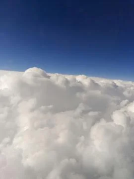 Close-up view of clouds from an airplane window against a blue sky Stock Photos