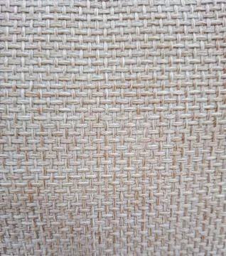 Close view of coarse light beige woven fabric showcasing a square cross hat.. Stock Photos