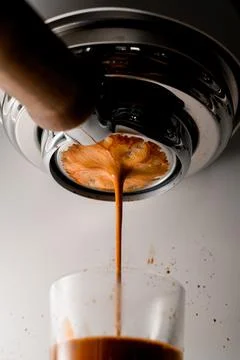 Close-up view of coffee being brewed by machine flowing through portafilter into Stock Photos