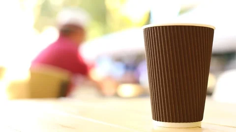 Close up view of coffee cup on table outside with sunny city on blurred backgrou 動画素材 117409094