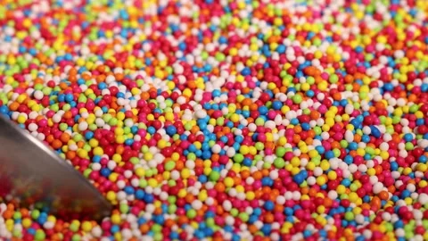 A close up view of colorful candy sprinkles being stirred by spoon in slow .. Stock Footage 332714421