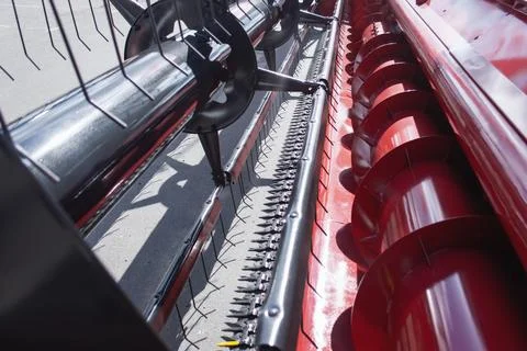 Close-up view of combine harvester header with rotating auger and cutting mec Stock Photos