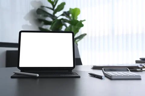 Close up view of computer tablet with empty screen, calculator on modern dark Stock Photos