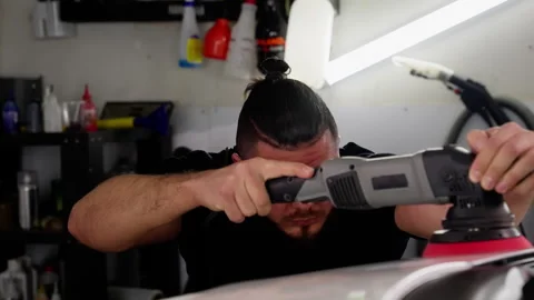 Close-up view of a concentrated mechanic buffing a car hood, engaging in Stock Footage 269214851