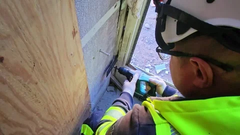 Close-up view of construction worker fastening window frame with cordless drill. Stock Footage 346410630