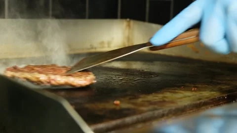 Close-up view of a cook in blue gloves using a press to smash and fry a fresh Stock Footage 317648476