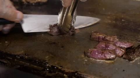 Close view cook cuts meat with metal knife and tongs Video stock 104841497
