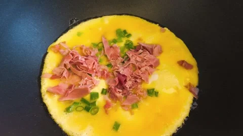 Close-up view of cooking an omelette as ham and sliced green onion egg in pan 動画素材 318130210