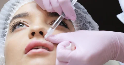 Close up view of Cosmetologist’s Hands Making the Injection. Process of Lip Stock Footage 91257434