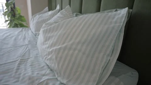 A close up view of a cozy bed with pillows and striped sheets in motion. Stock Footage 332140943