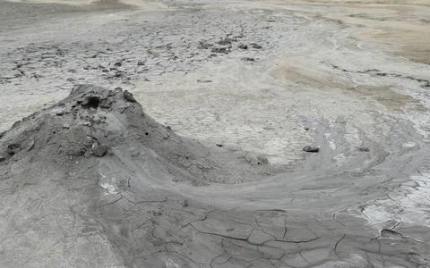 Close up view on crater of mud volcano. Slow flow of underground mud (mixed o Stock Photos