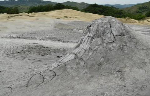 Close up view on crater of mud volcano. Slow flow of underground mud (mixed o Stock Photos