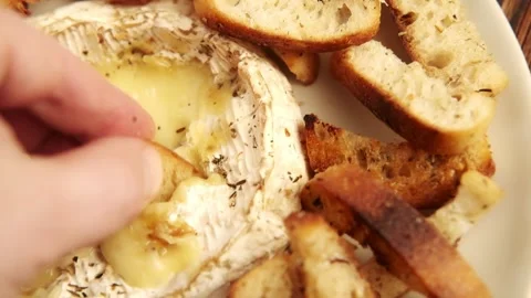 A close-up view of a crispy bread bite being held, ready to be dipped into a Stock Footage 277546637