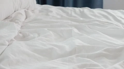 Close up view of crumpled white bed sheets and pillow in bed in morning lig.. Stock Footage 333259962