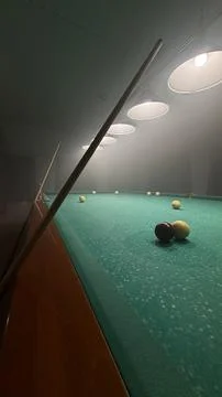 Close view of a cue stick lying on a green pool table with a few balls Foto stock