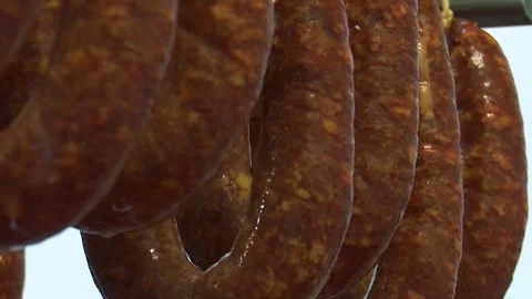 Close up view of cured sausages hanging on metal racks detailed shot showcasing Vídeo Stock 342842768