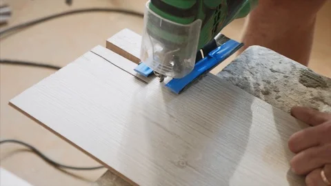A close-up view of cutting a hole on a piece of laminate with electric jigsaw. Stock Footage 116889132