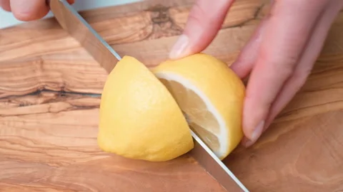 Close up view of cutting a lemon into half on the wooden cutting board in 4k. Stock Footage 140766339