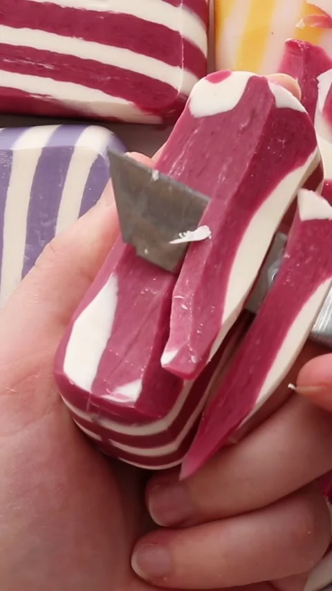 A close-up view of cutting a red soap bar with white stripes, revealing smooth Vídeos de archivo 311046238