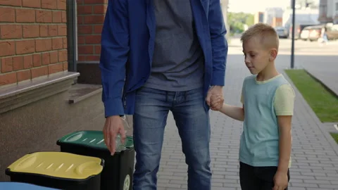 Close view of the dad with son holding the plastic bottle and put it into the Stock Footage 203807471