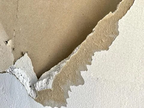 Close up view of damaged white drywall wall surface with peeling paper layer Stock Photos