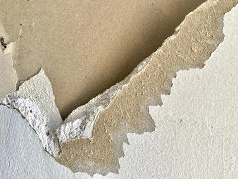 Close up view of damaged white drywall wall surface with peeling paper layer Stock Photos