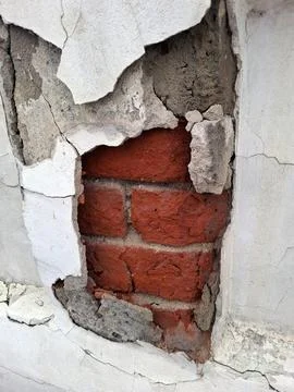 Close up view of a damaged white plaster wall uncovering old red bricks und.. Fotos de archivo
