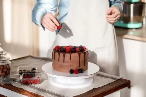 Close up view of decorating chocolate cake with berries. Stock Photos