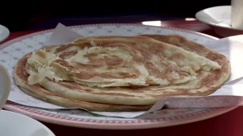A close-up view of a delicious breakfast showcasing paratha and tea at a 스톡 동영상 291839831